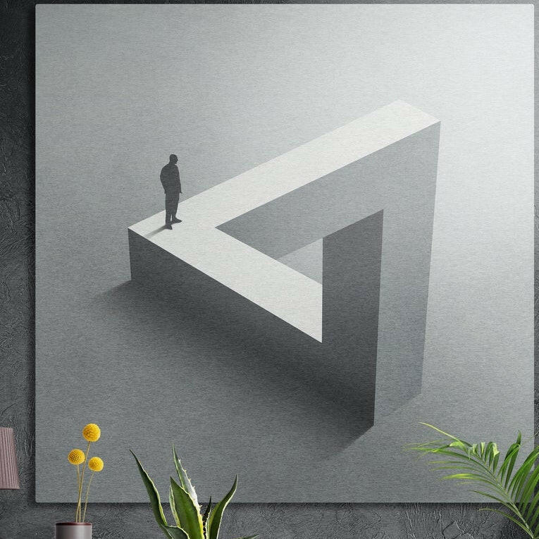 Small figure standing on a gray impossible triangle loop, brushed aluminum wall art behind plants