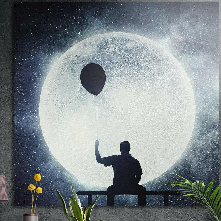Silhouette of a man on a bench holding a black balloon before a huge glowing full moon, brushed aluminum wall art