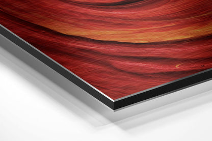 Red spiral swirl abstract brushed aluminum panel corner close-up showing the brushed metal grain