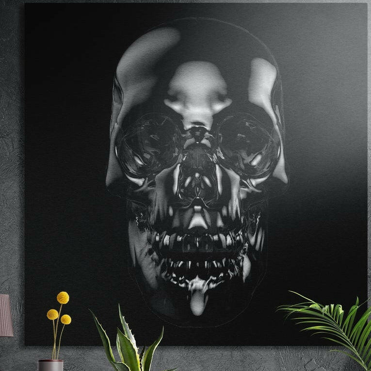 Polished chrome skull on a black background, brushed aluminum wall art on a concrete wall behind plants