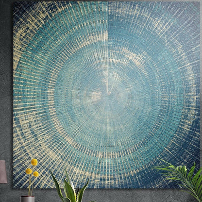 Blue and cream radial line abstract from one center point, brushed aluminum wall art on a dark wall behind plants