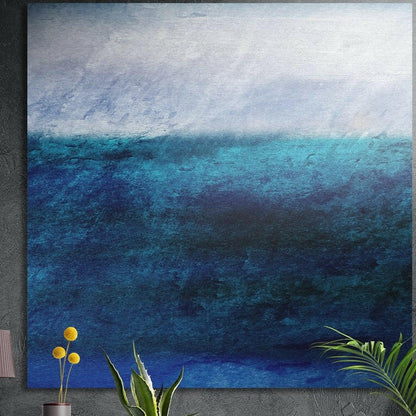 Textured deep blue sea meeting a pale misty sky in a soft abstract seascape, brushed aluminum wall art above potted plants