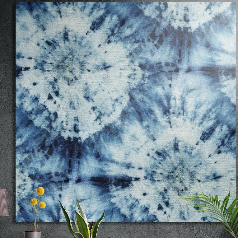 Indigo and white tie-dye pattern abstract, brushed aluminum wall art on a concrete wall behind plants