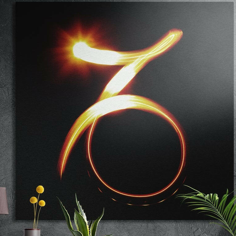 Capricorn zodiac glyph in glowing golden light trails on black, brushed aluminum wall art on a concrete wall behind plants