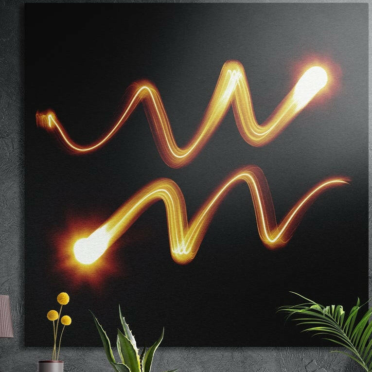 Aquarius zodiac glyph as two glowing orange light trail waves on black, brushed aluminum wall art behind plants