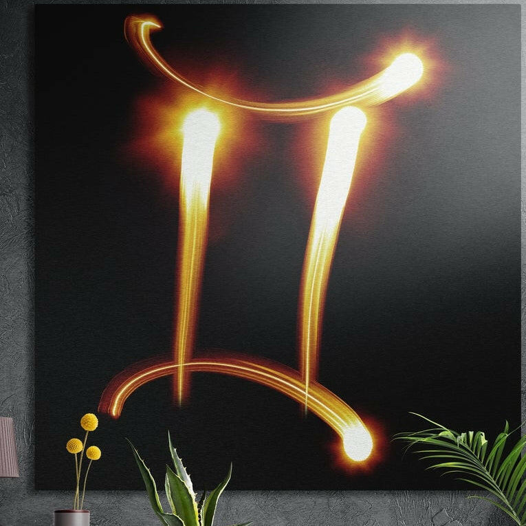 Gemini zodiac glyph in glowing orange and gold light trails on black, brushed aluminum wall art behind plants