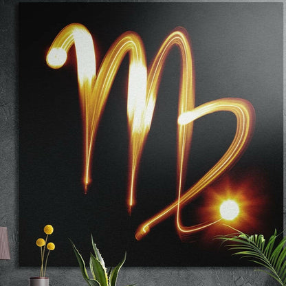 Gold light trail drawing the Virgo glyph with a starburst on black, brushed aluminum wall art behind plants