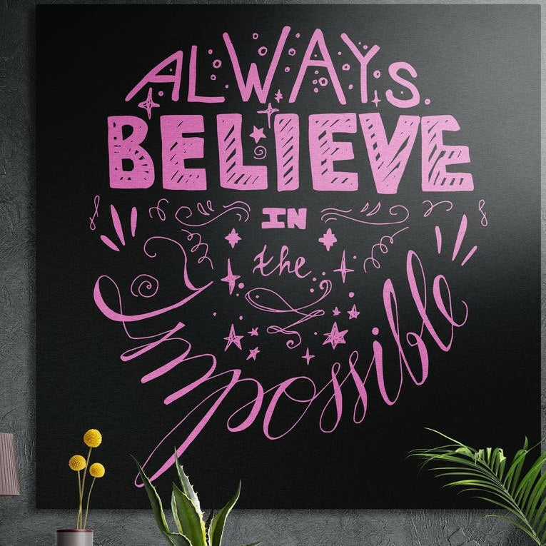 Pink hand lettered quote beginning Always Believe with swirls and stars on black, brushed aluminum wall art