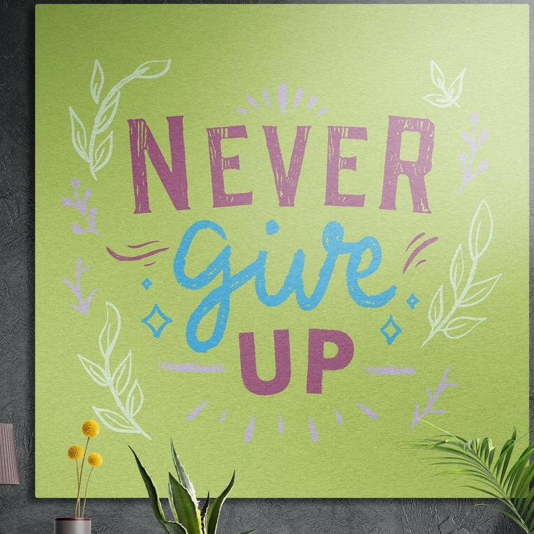Never Give Up lettering in plum and blue on lime green with leaf sprigs, brushed aluminum wall art behind plants