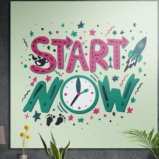 Pink and green Start Now lettering with a clock and rocket, brushed aluminum wall art on a dark wall behind plants