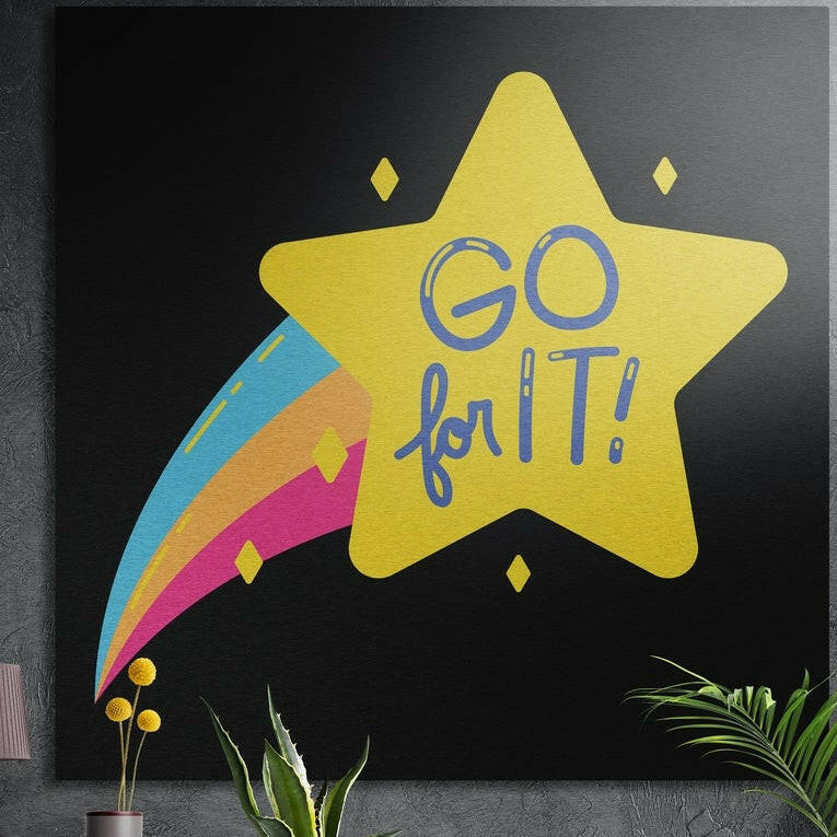 Yellow shooting star with a rainbow trail and Go for It lettering on black, brushed aluminum wall art behind plants