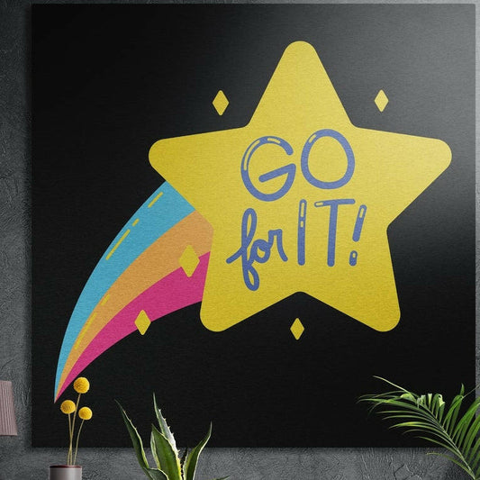 Yellow shooting star with a rainbow trail and Go for It lettering on black, brushed aluminum wall art behind plants