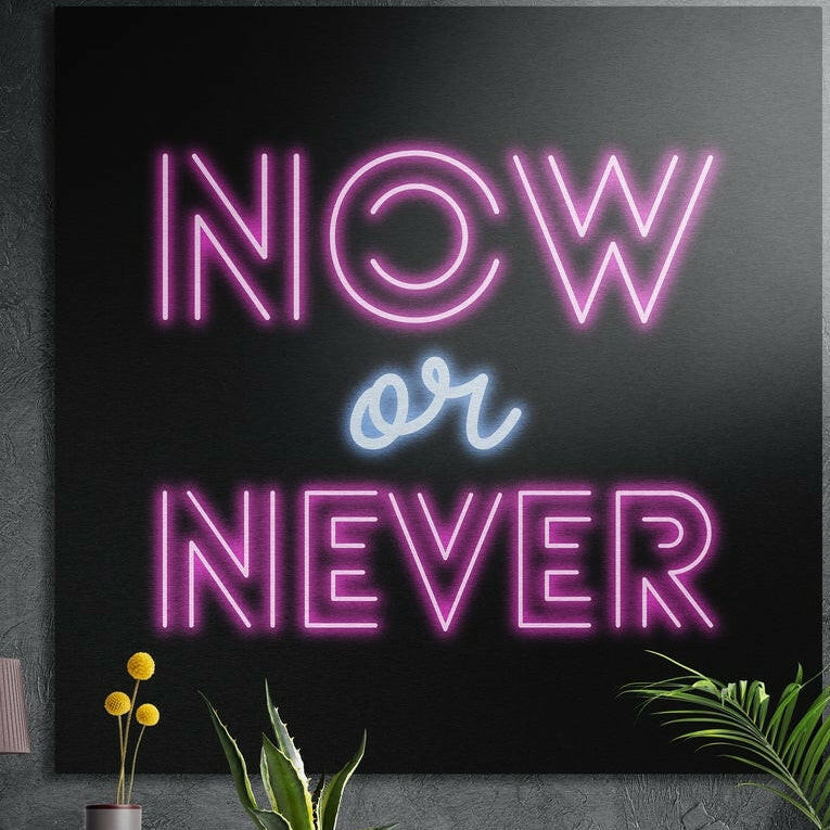 The words Now or Never in pink neon-style lettering with a blue script or, on black, brushed aluminum wall art