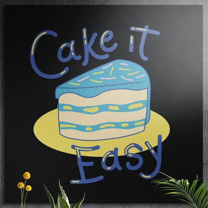 Blue frosted cake slice on a yellow plate with playful lettering, brushed aluminum wall art behind plants