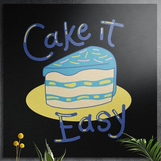 Blue frosted cake slice on a yellow plate with playful lettering, brushed aluminum wall art behind plants