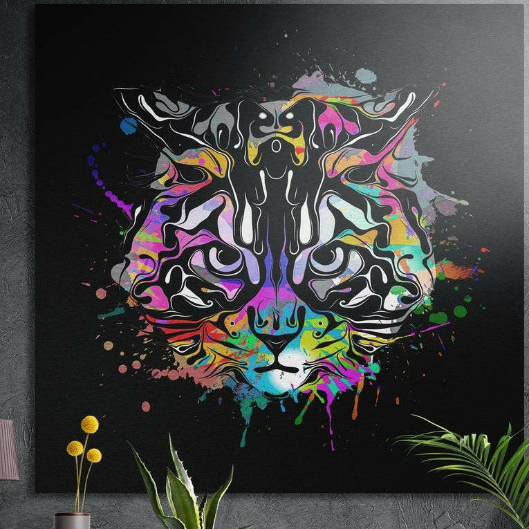 Colorful paint splash cat face on black, brushed aluminum wall art on a concrete wall behind plants