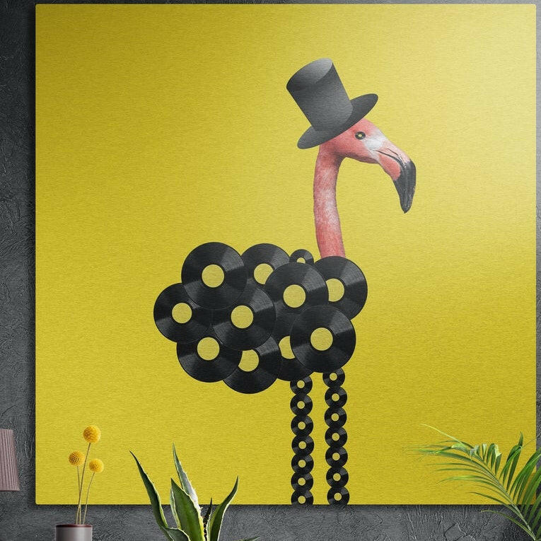 Flamingo in a top hat with a body of vinyl records on yellow brushed aluminum wall art on a gray concrete wall above plants