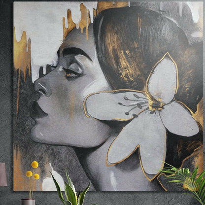 Woman in gray profile with a gold-edged white flower in her hair, brushed aluminum wall art on a concrete wall behind plants