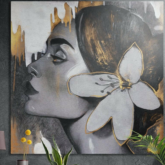 Woman in gray profile with a gold-edged white flower in her hair, brushed aluminum wall art on a concrete wall behind plants