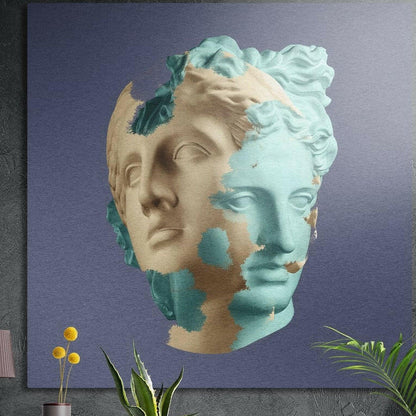 Teal and tan double statue face brushed aluminum wall art on a gray wall above yellow flowers and plants