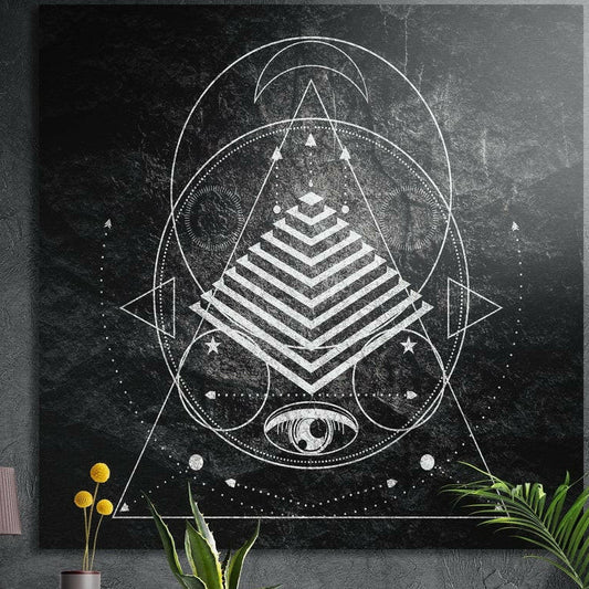 Sacred geometry pyramid and eye square brushed aluminum wall art on a gray concrete wall with plants in front