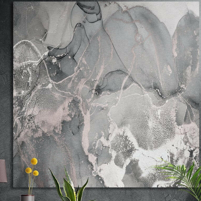 Gray and blush pink marble ink artwork as brushed aluminum wall art on a dark concrete wall behind yellow flowers and plants