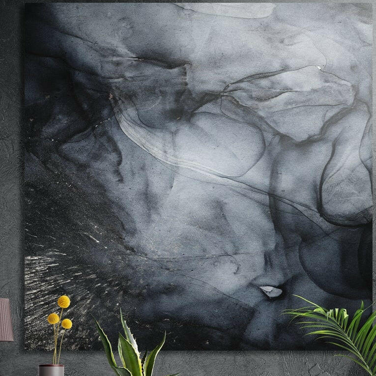 Charcoal smoke ink abstract brushed aluminum wall art on a dark wall above yellow flowers and plants