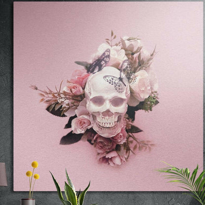 Blush pink rose and butterfly skull brushed aluminum wall art on a dark concrete wall behind potted plants