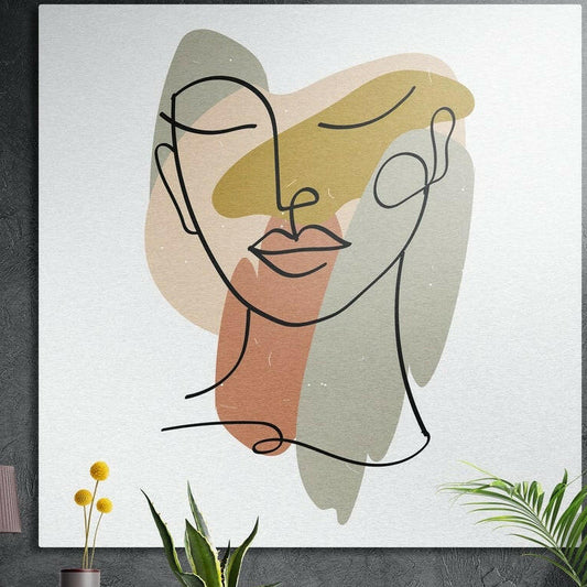 One line woman face with pastel shapes brushed aluminum wall art hung on a dark textured wall above potted plants