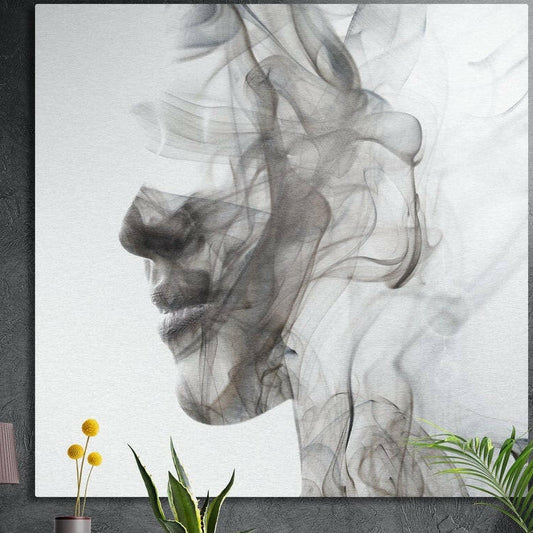 Smoke profile face brushed aluminum wall art on a dark concrete wall above yellow flowers and plants