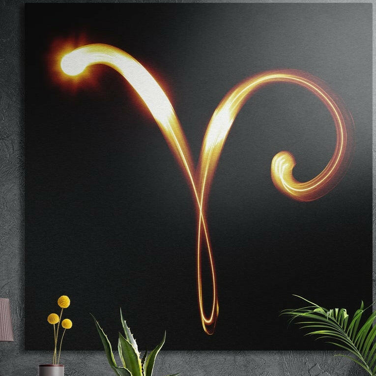 Aries zodiac sign in flaming gold light brushed aluminum wall art on a gray concrete wall above plants