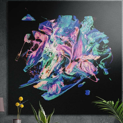 Pink and teal paint burst brushed aluminum wall art on black, square, on a dark wall behind potted plants