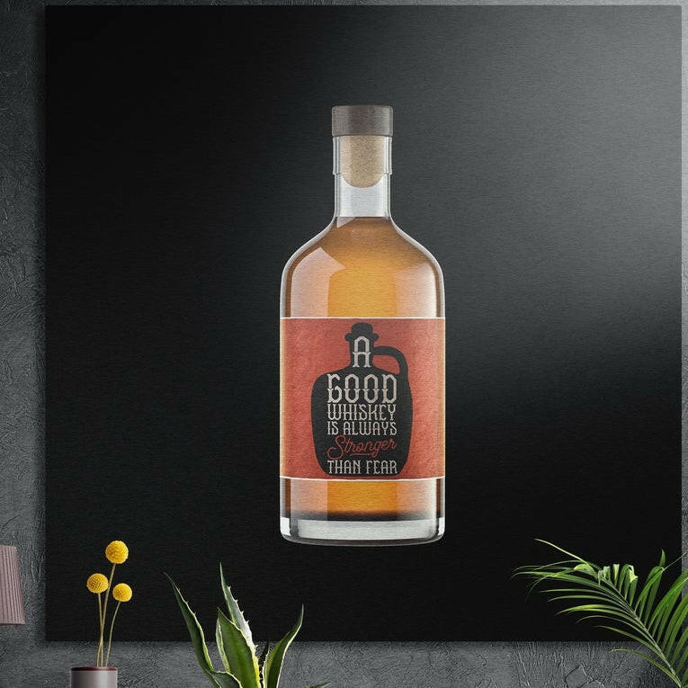 Whiskey bottle brushed aluminum wall art on a dark concrete wall above a vase and plants