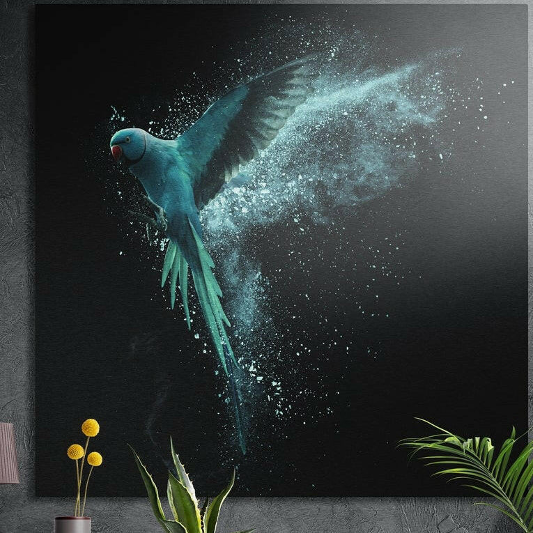 Teal parrot dissolving into particles on black, brushed aluminum wall art on a dark concrete wall behind plants