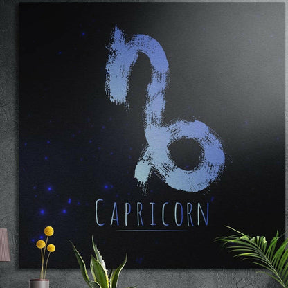 Capricorn zodiac sign in blue brushstrokes brushed aluminum wall art on a gray concrete wall above plants