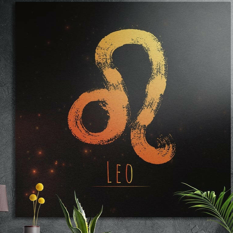 Leo zodiac sign in golden orange brushstrokes brushed aluminum wall art on a gray concrete wall above plants