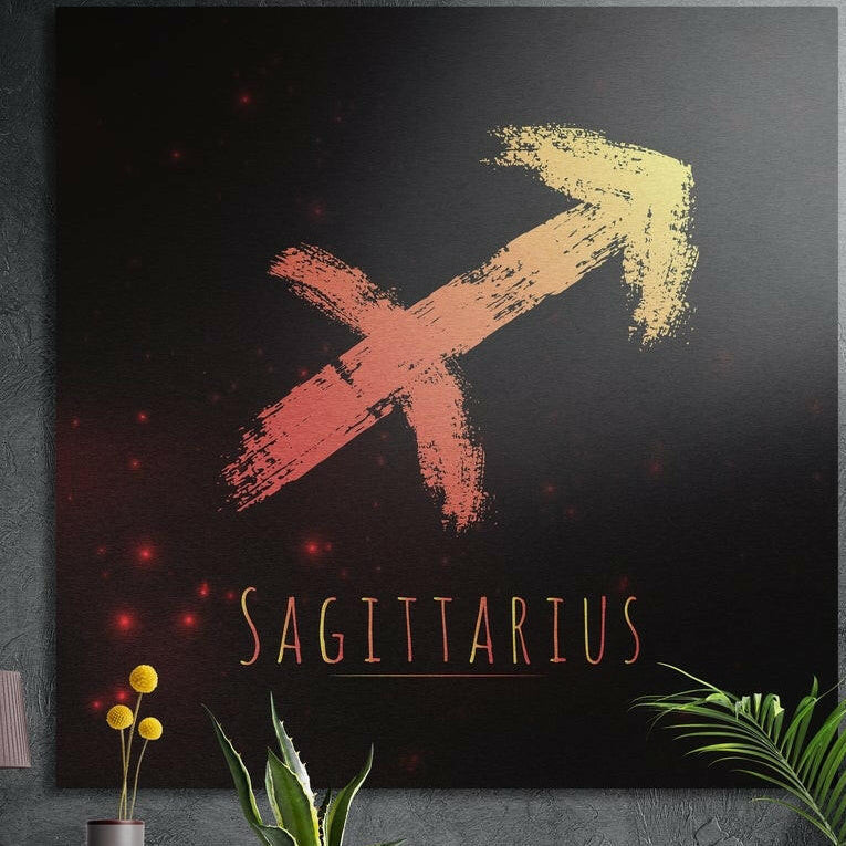 Sagittarius zodiac sign in coral gold brushstrokes brushed aluminum wall art on a gray concrete wall above plants