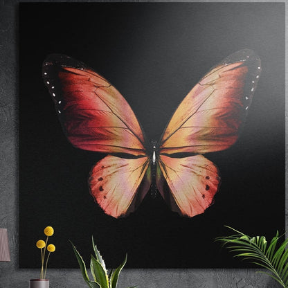 Coral orange butterfly on black brushed aluminum wall art on a dark wall behind a vase of yellow flowers and plants