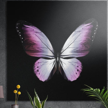 Pink and white butterfly on black, square brushed aluminum wall art on a gray wall behind plant leaves