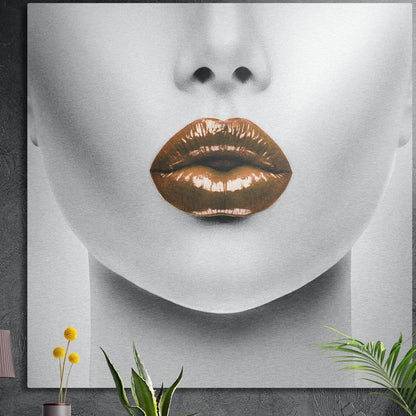 Bronze lips on a pale face close-up, square brushed aluminum wall art on a dark concrete wall with plant leaves below