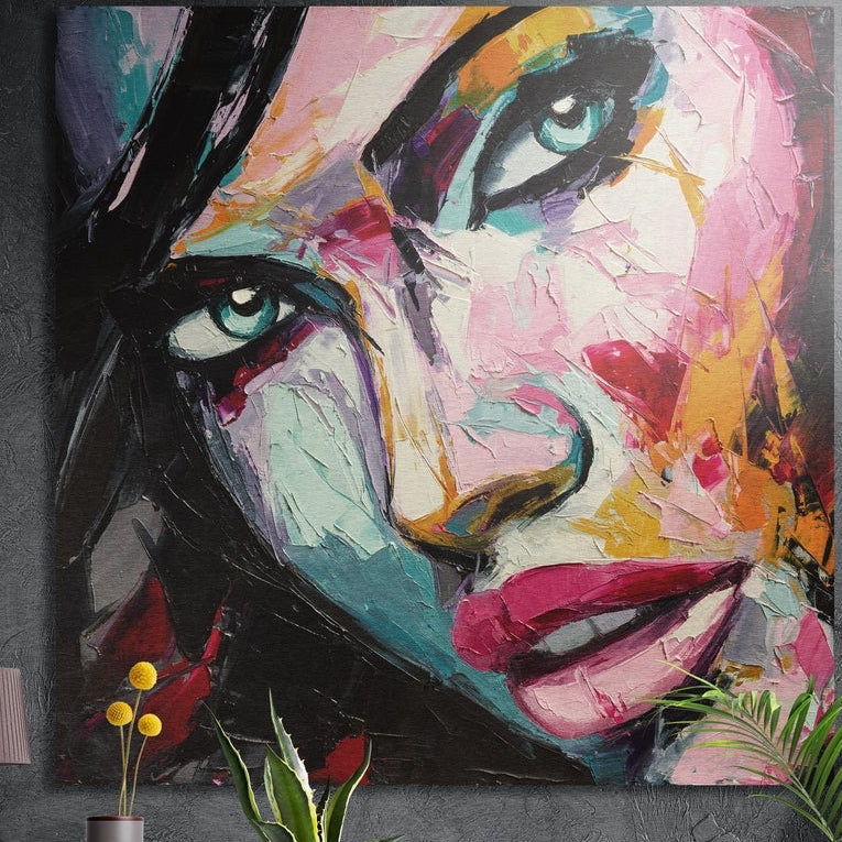 Colorful woman face in bold strokes brushed aluminum wall art on a gray wall above yellow flowers and plants