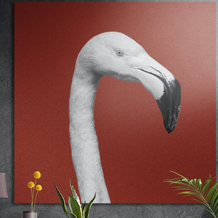 White flamingo head and neck on a brick red background, brushed aluminum wall art on a gray wall above yellow flowers