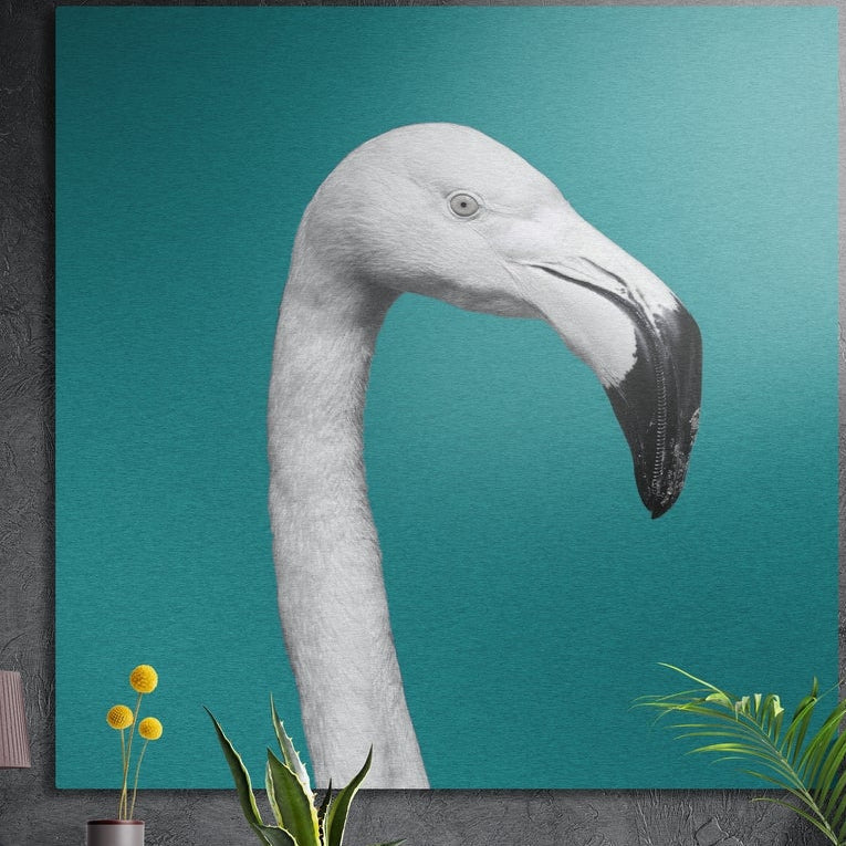 White flamingo head and curved neck on teal brushed aluminum wall art on a gray concrete wall above plants