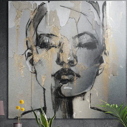 Gold and gray sketched woman face brushed aluminum wall art hung on a dark textured wall above potted plants