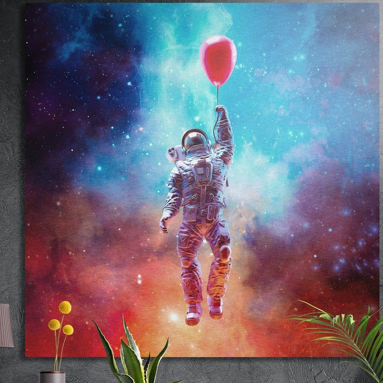 Astronaut with red balloon in a nebula square brushed aluminum wall art on a gray concrete wall with plants in front