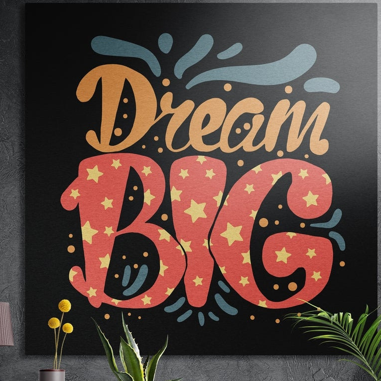 Dream big starry red lettering brushed aluminum wall art on a dark textured wall above potted plants