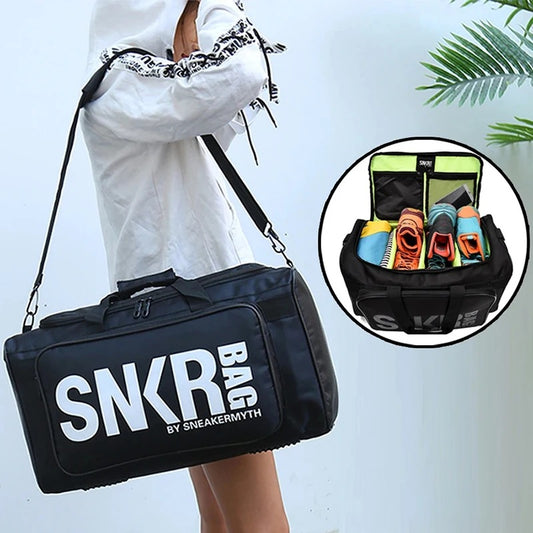 A black sports shoe travel bag with the text 'SNKR BAG' on the side, displayed alongside its contents which include sneakers, clothes, and gear organized in separate compartments, indicating the bag's large capacity and compartmentalization.