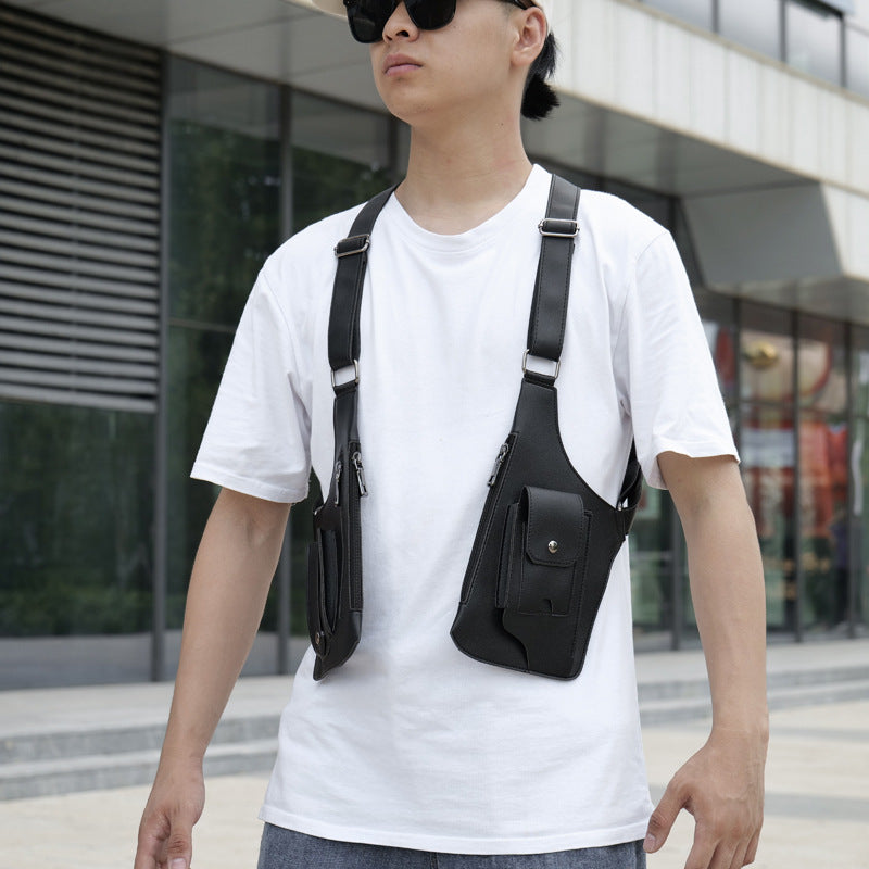 A person wearing a white t-shirt and sunglasses is carrying a black UrbanFlex Tactical Shoulder Bag which is slung over the shoulder and hip, showcasing the bag's multiple pockets and the sleek design.