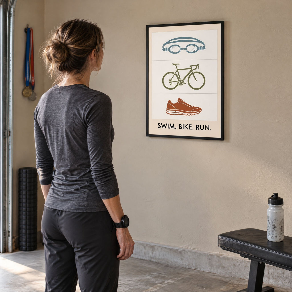 A triathlete standing back to look at the framed swim bike run print in their training room