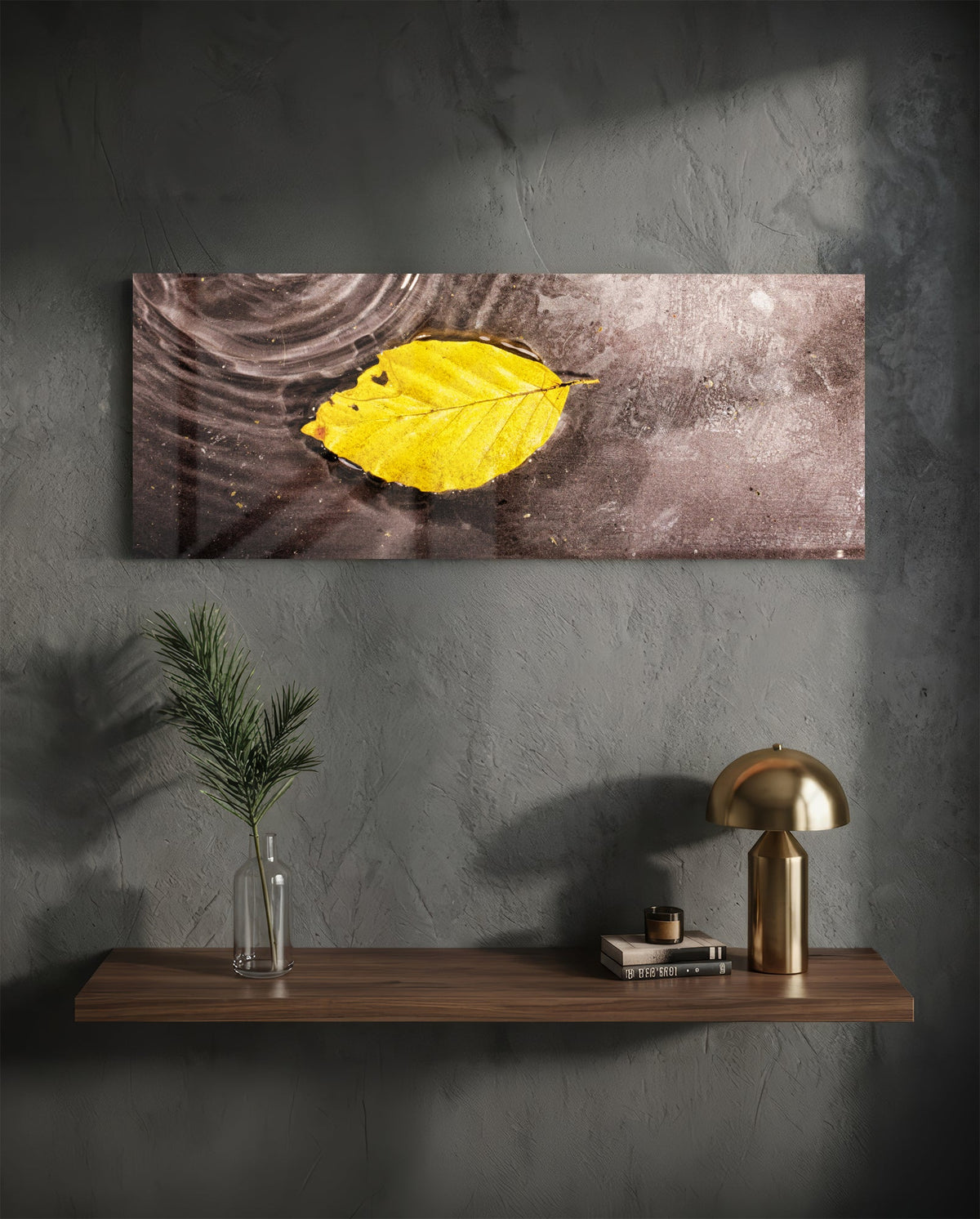 Yellow leaf on rippled water glass wall art above a floating shelf with a brass lamp and a plant in a vase